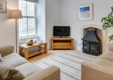 26 Wesley Place, St Ives is a beautifully updated stone cottage on a quiet central lane, featuring two inviting sitting rooms, a peaceful walled courtyard garden, and charming attic bedroom with rooftop sea views towards the coast beyond.