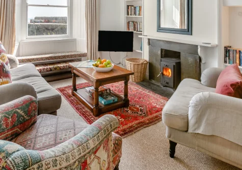 6 Fishermans Square, Mousehole is a captivating fisherman's cottage perched on the harbour wall in this lovely Cornish village, boasting spectacular sea views across Mount's Bay, character-filled interiors with cosy wood burner, and beaches nearby.