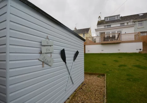 The enclosed lawned garden, with secure storage for bikes & surfboards, at A Rare Old Station, Appledore