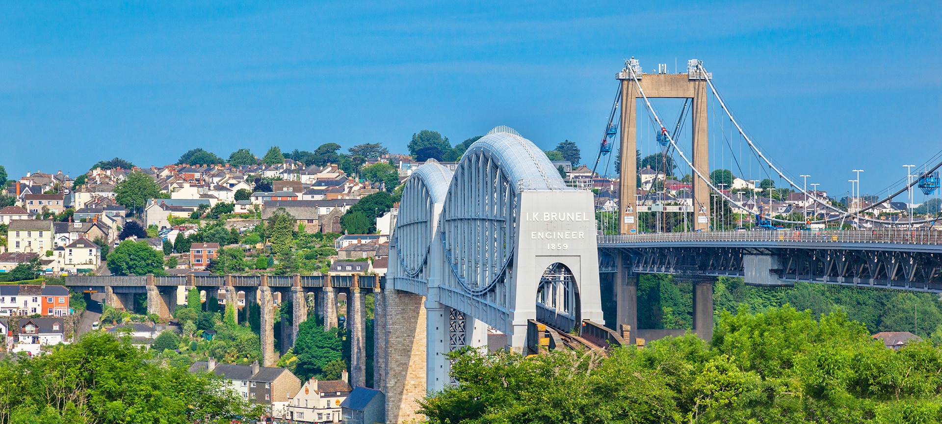 The Royal Albert Bridge is a railway bridge which spans the River Tamar in England between Plymouth, Devon and Saltash, Cornwall. Its unique design consists of two 455-foot (138.7 m) lenticular iron trusses 100 feet (30.5 m) above the water, with conventional plate-girder approach spans. This gives it a total length of 2,187.5 feet (666.8 m). It carries the Cornish Main Line railway in and out of Cornwall. It is adjacent to the Tamar Bridge which opened in 1962 to carry the A38 road.