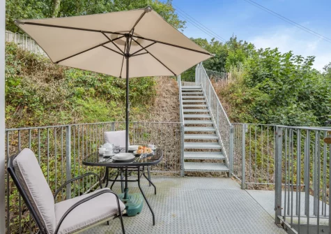 The alfresco dining area, with steps leading up to the enclosed lawned garden, at April Cottage at Sanctuary Farm, Woodford