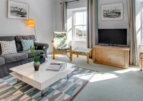 Aquarius, Porthcurno is a stylish three-bedroom apartment in a characterful former college building, offering sea glimpses, contemporary interiors, shared tennis courts, and effortless access to the iconic Minack Theatre and world-class beach.