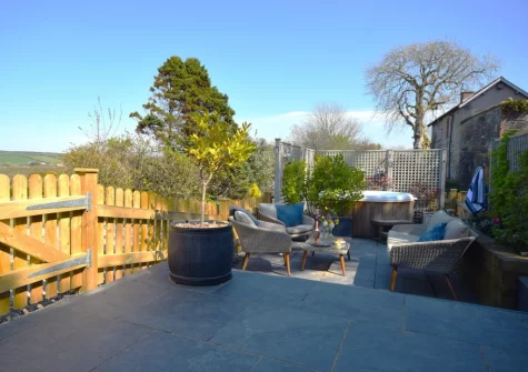 The enclosed tiered sun-trap patio, outdoor sitting area & hot tub at Azalea Barn, Lee