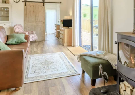 Bailey Lodge, Barnstaple is a beautiful Scandinavian-style retreat in peaceful North Devon countryside, featuring exposed oak beams, a cosy wood burner, wraparound decked balcony, and easy access to stunning beaches and Exmoor National Park.