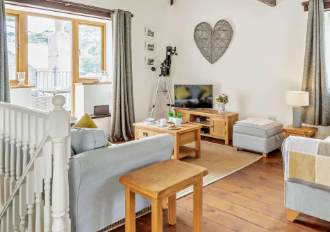 Banjo Cottage, Looe is a charming two-bedroom Grade II-listed barn conversion in the heart of East Looe, featuring a south-facing balcony with sea views, characterful beamed interiors, and the sandy beach just 150 metres from your door.