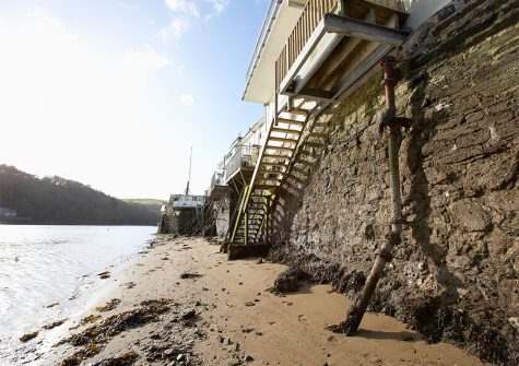 Steps leading down to the sandy water's edge from the balcony at Barnacles, Fowey
