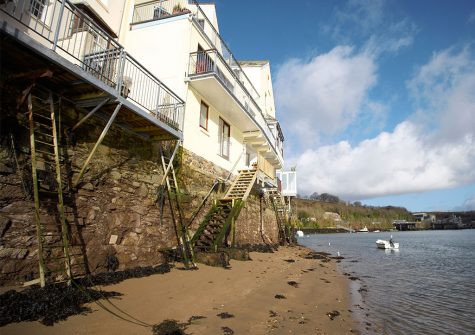 Steps leading down to the sandy water's edge from the balcony at Barnacles, Fowey