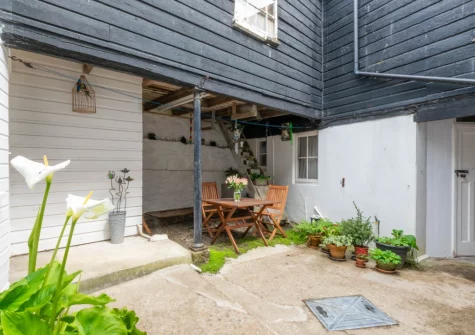 The enclosed courtyard garden with green potted plants, barbecue & alfresco dining area at Carvosso, Mousehole