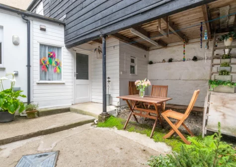 The enclosed courtyard garden with green potted plants, barbecue & alfresco dining area at Carvosso, Mousehole
