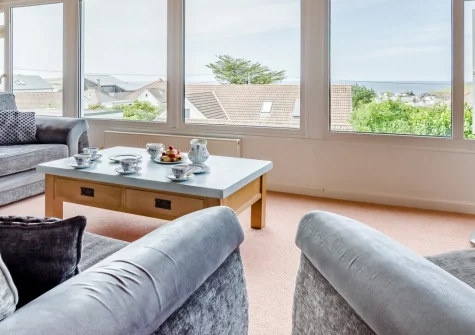 Chy Lymner, Trevone is a spacious four-bedroom house just moments from the coast, featuring spectacular Atlantic Ocean views from panoramic first-floor windows, an enclosed garden perfect for dogs, and easy access to Trevone's beaches and clifftops.