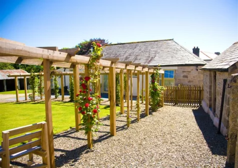 The shared lawn with pretty pergolas at Dickins' Cottage, Trenarlett Farm, St Breward