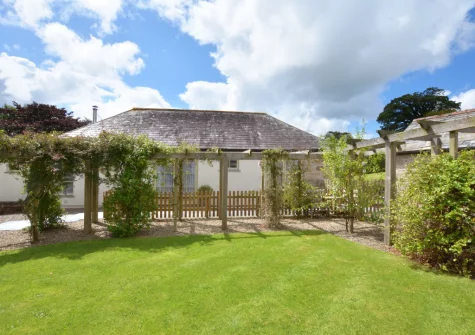 The shared lawn with pretty pergolas at Dickins' Cottage, Trenarlett Farm, St Breward