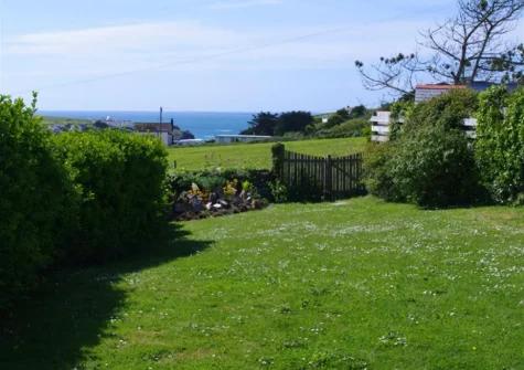The enclosed garden, bordered by mature shrubs, at Farmlands, Porthcothan