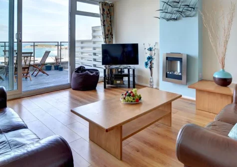 Fiddlers Green, Newquay is a light-filled two-bedroom apartment just 650 metres from legendary Fistral Beach, featuring a sun-drenched balcony with coastal views, shared heated outdoor pool, and perfect positioning for surfing and seaside adventures.