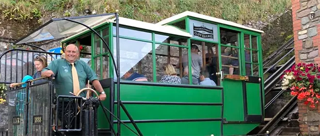 The 131m long Lynton and Lymouth Cliff Railway (LLCR) was handcarved out of the cliff and took three years to complete. Two passenger cars, joined by a cable, work by gravity. The lower car releases water from its 700 gallon tank into the river to make it lighter than the upper car. When the brake is released (hydraulically operated, of course!) the car rises up the steep 45 degree cliffside while the heavier top car descends.