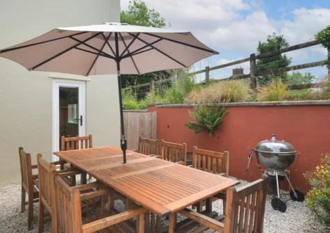 The sheltered, sunken, gravelled barbecue & alfresco dining area at Higher Treliver Farmhouse, St Wenn