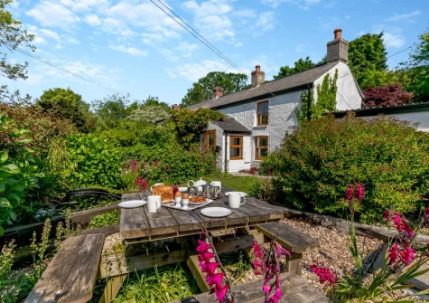 The beautifully manicured front garden & alfresco dining area at Hollow Tree Cottage, Cambrose