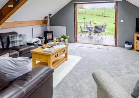 Horseford Snug, East Worlington is a beautifully converted barn in rural Mid Devon, boasting exposed beams, a cosy wood burner, and an enclosed garden with panoramic countryside views where deer and red kites are regular visitors.