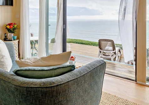 Infinity, Freathy is a spectacular cliff-top retreat with floor-to-ceiling windows framing sweeping Atlantic views, featuring a private hot tub on the deck, luxurious interiors, and direct access to golden beaches and coastal paths.