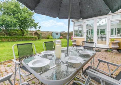 The patio, alfresco dining area & enclosed lawned garden at Little Birds, St Merryn