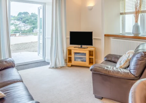 Manor House, Looe is a wonderfully light apartment overlooking the river in this enchanting Cornish fishing town, featuring a private patio with water views, modern interiors, and the golden sands of Looe Beach just 300 metres away.