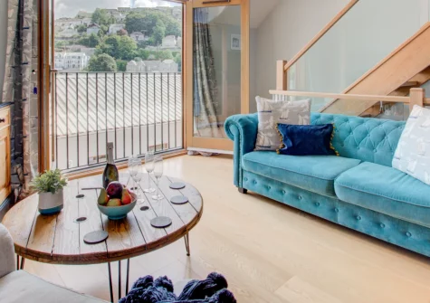 Number One at The Creekside, Looe is a beautifully designed two-bedroom duplex apartment with stunning estuary views from a Juliet balcony, featuring a stylish mezzanine relaxation space, contemporary interiors and private parking.