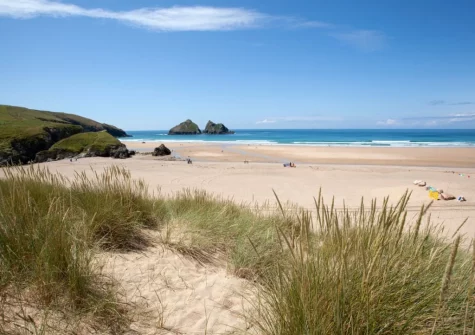 HolyWell Bay Beach is a beautiful wide sandy beach backed by grassy dunes and surrounded by rugged headlands & rocky islands