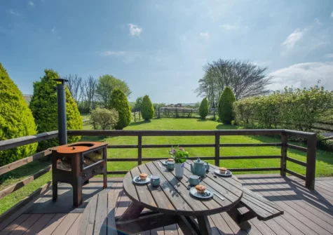 The decked patio, wood burner with cooking facilities & alfresco dining area at Old Dairy Barn, Challacombe