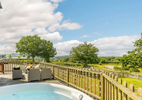 The patio, outdoor sitting area & hot tubwith far-reaching countryside views at Otter Barn Lakes, St Giles-on-the-Heath