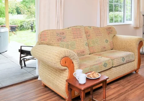 Pendavey Lodge, Sladesbridge is a beautifully presented two-bedroom cottage set in expansive gardens with a private hot tub, direct access to the Camel Trail, and stunning countryside views, perfectly placed for exploring North Cornwall's beaches.
