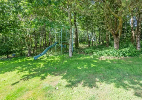 The garden with children's play area, and pretty private woodland area with walks to explore, at Penvith Farmhouse, Saint Martin-by-Looe