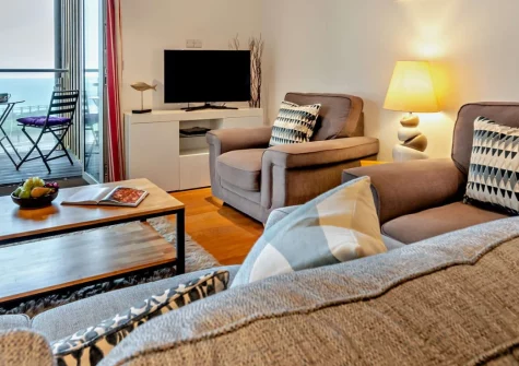 Porth Apartment, Newquay is a wonderfully comfortable first-floor retreat opposite secluded Whipsiderry Beach, featuring a private balcony with spectacular ocean views, contemporary coastal interiors, and direct access to golden Porth Beach.