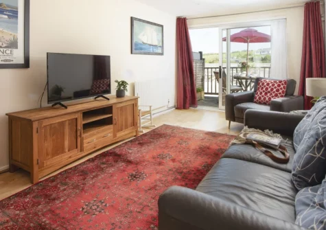 Porth Beach House at Mermaid Court, Newquay is a beautifully appointed two-bedroom beachfront apartment just steps from golden Porth Beach, featuring a furnished balcony with spectacular sea views, contemporary open-plan living spaces, and parking.