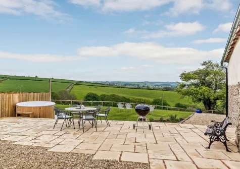 The patio, alfresco dining area & wood-fired hot tub at Priestacott Tithe Barn, Torrington
