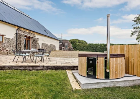The patio, alfresco dining area & wood-fired hot tub at Priestacott Tithe Barn, Torrington