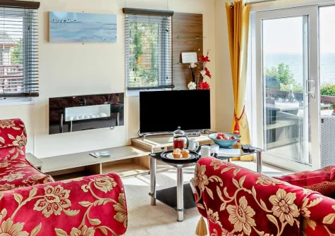 Riviera Bay, Brixham is a contemporary single-storey lodge above St Mary's Bay, featuring a spacious decked veranda with stunning sea views, flexible accommodation for six guests, and direct access to the coastal path and secluded beach below.