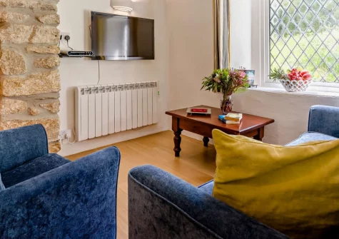 Sarah's Cottage, Camelford is a lovely two-bedroom retreat nestled in peaceful Cornish countryside near Bodmin Moor, featuring original beams, granite fireplace with wood-burner, and welcoming two dogs to explore moorland walks and nearby coast.
