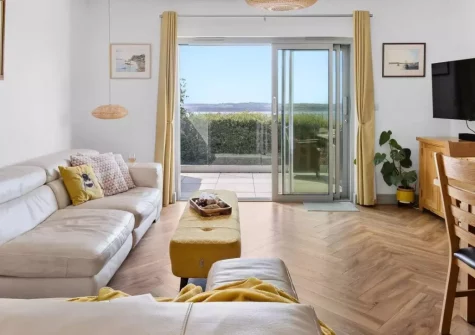 Seacroft, Torquay is a stylish three-bedroom house with sweeping panoramic bay views from two balconies, elegant interiors, en-suite bedrooms, and a private patio, perfectly placed for beaches, dining and coastal walks on the English Riviera.