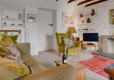 St Michaels, Porthleven is a characterful cottage perched above the historic harbour with spectacular sea views, featuring original beams, an open fire, bohemian interiors, and a secret garden across the road for watching dolphins and waves.