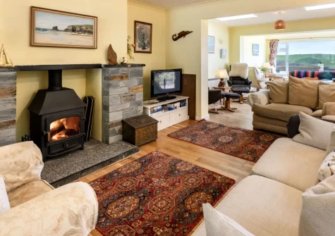 Stradav, Polzeath is a spacious five-bedroom home with sweeping sea views, a sunny balcony, and a wood-burning stove, just moments from the beach and glorious coastal paths, perfect for family holidays and gatherings with friends all year round.