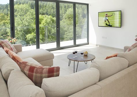 Teign Vale, Drewsteignton is a contemporary barn surrounded by stunning river and woodland views. Bifold doors provide views from the comfortable sitting/dining room, modern kitchen & all three ensuite bedrooms. Games barn & garden near Castle Drogo.
