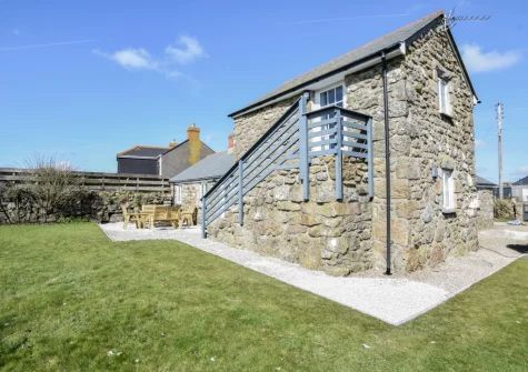 The patio, alfresco dining area & large enclosed lawned garden at The Byre, Sennen
