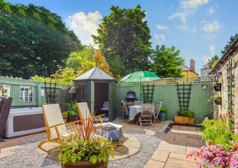 The enclosed garden, with alfresco dining, sitting area, summer house & hot tub at The Churns, Lanhydrock