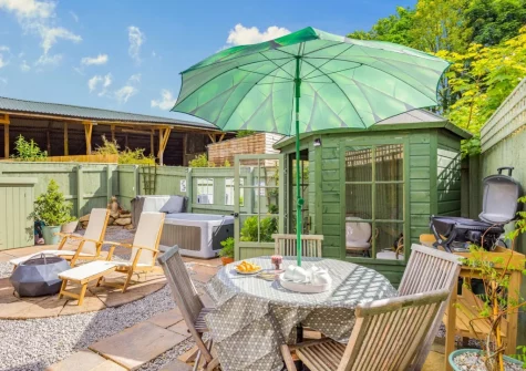 The enclosed garden, with alfresco dining area & summer house, at The Churns, Lanhydrock