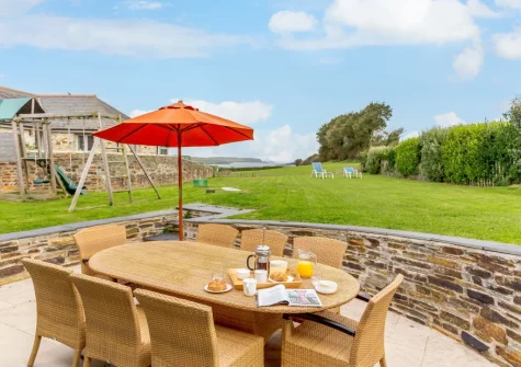 The patio, alfresco dining area, children's play area & large enclosed garden at The Dreyhouse, St Issey