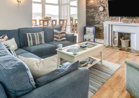 The Gulls, Looe is a stunning four-bedroom waterfront home in West Looe, boasting outstanding panoramic views across the river and golden beach, four en-suite bedrooms, and a glass-wrapped dining area perfect for sunset dinners above the town.