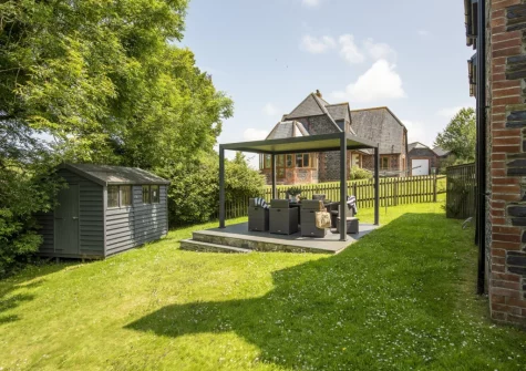 The pergola-covered patio, barbecue, alfresco dining area & garden at The Hawthorns at Roserrow, Polzeath