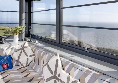 The Lookout Tower, Beer is a two-bedroom clifftop retreat perched atop Beer Head, boasting panoramic coastal views, a private sauna, outdoor terraces, and a pneumatic lift connecting luxurious living spaces in an Area of Outstanding Beauty.