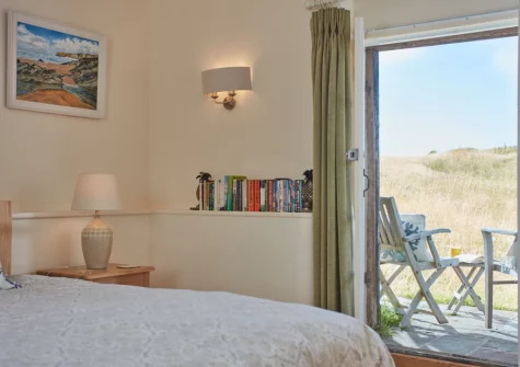 The bedroom, with small patio & outdoor sitting area, at The North Wing at Trevigue, Crackington Haven