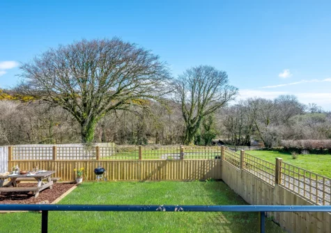Step down into the enclosed garden, with barbecue, alfresco dining area & woodland views